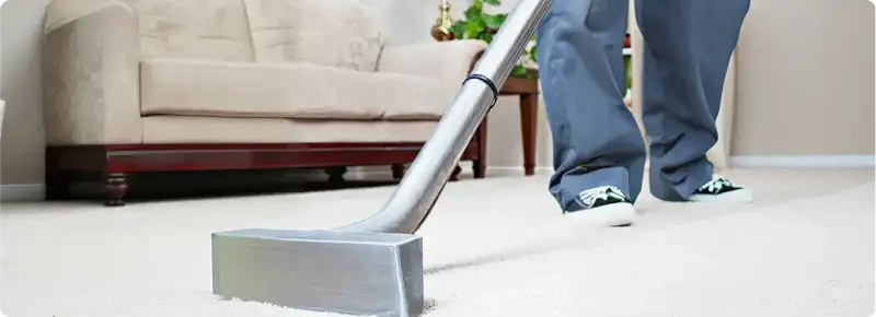 Carpet cleaning technician using a hot-water extraction wand on a light-colored carpet in a living room, Albany, NY.